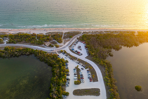 Parking lot at Florida Blind Pass beach on Manasota Key, USA. Vehicle parking area with cars parked on ocean beach parking lot. Summer vacation on beachfront.