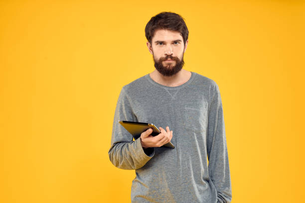 istock Emotional man with tablet in hands technology internet device lifestyle yellow background 2136052254