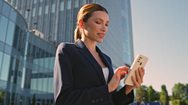 istock Smiling executive texting mobile phone on sunny business district close up. 2136055463