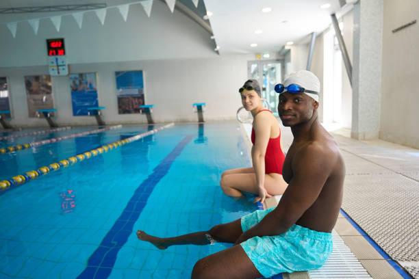 istock Two young athletes resting together at poolside 2136064634