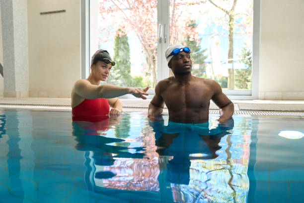 Swimming coach pointing at something to her student in pool during aqua workout