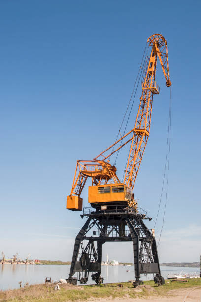 Port industrial cranes at river unloading depot on clear sunny day