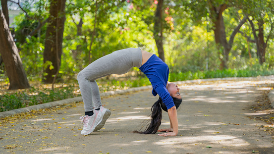 A beautiful Woman performing Chakrasana yoga pose, also known as Wheel Pose, Concept of a Healthy lifestyle