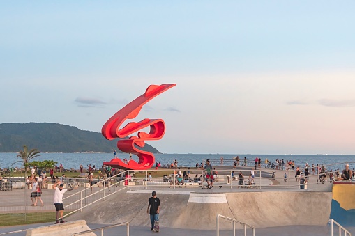 City of Santos, Brazil. 31.03.24. Emissary Park. Skateboard rink and sculpture by Tomie Ohtake in honor of 100 years of Japanese immigration to Brazil. In the background, the sea and horizon at sunset