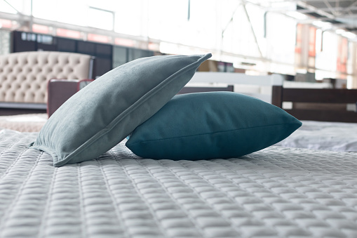 Two soft grey and blue pillows on a white bedspread close-up