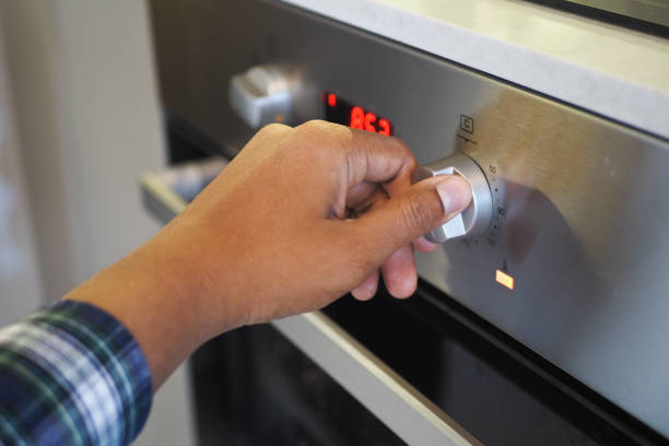 istock Close up of men hand setting temperature control on oven. 2136153931