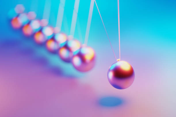 Pendulum illuminated by pink and blue lights on purple background. Horizontal composition.