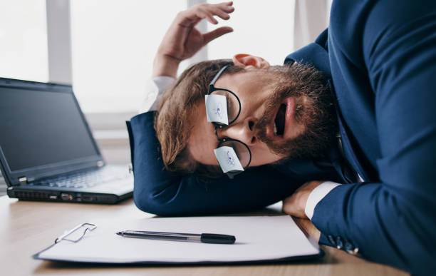 istock Business man sleeping at work wearing glasses with sheets of paper 2136179978