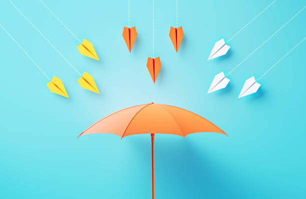 Paper Planes Flying Towards A Coral Colored Umbrella On Blue Background stock photo