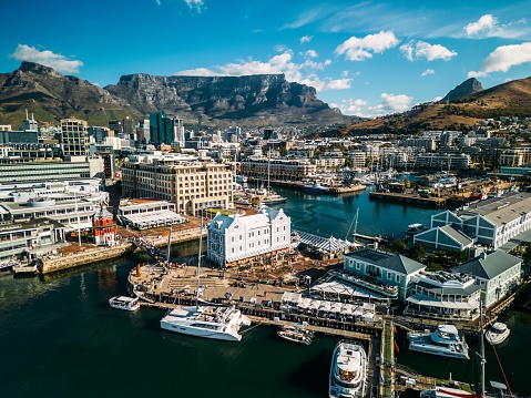 Cape Town, South Africa - April 2, 2024: Busy day at the VA Waterfront, seen from above with Table Mountain and downtown Cape Town in the background