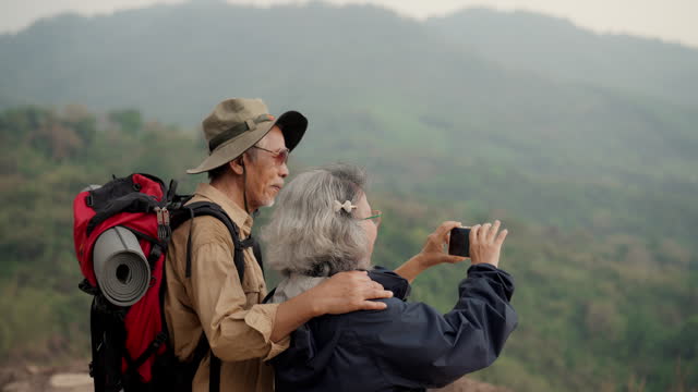 Active senior couple unwind, gazing at a majestic mountain.