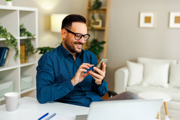 istock Young smiling man is using a smartphone in home office 2136270192