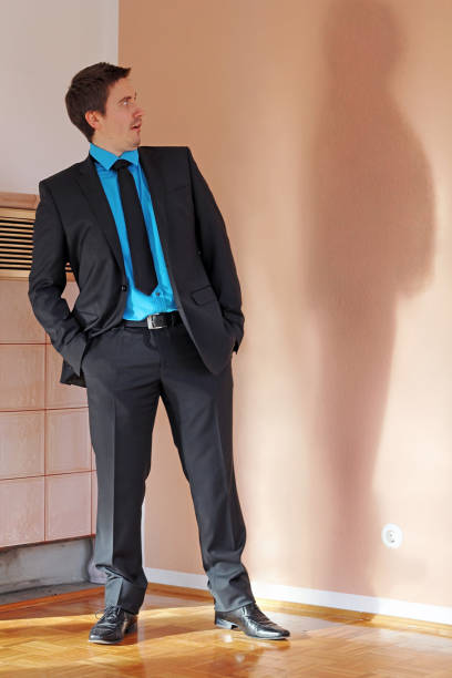 istock A man in a suit is frightened by his thicker shadow 2136283657