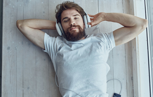 bearded man in headphones lies on the windowsill music leisure lifestyle. High quality photo