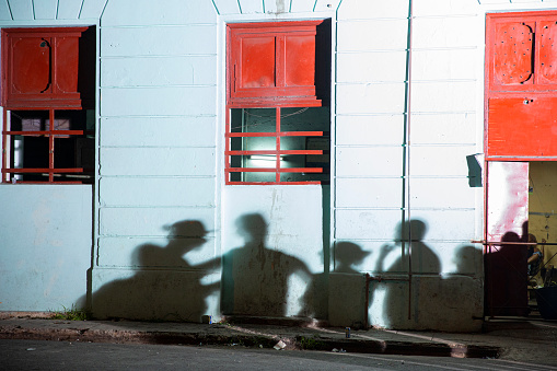 Shadows of a small group of people cast on a blue wall at night