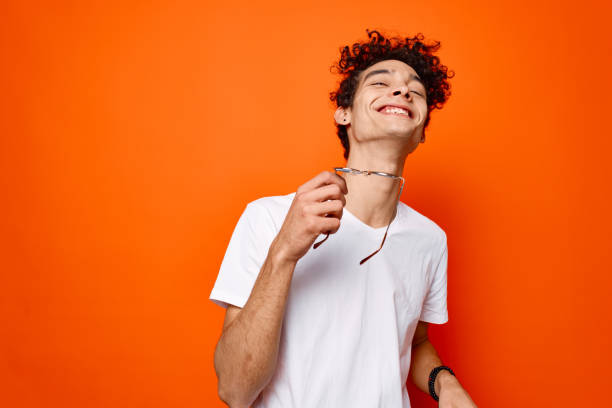 istock guy with curly hair sunglasses in hands cropped view orange background 2136375497