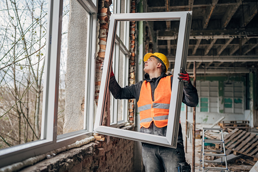 Skilled craftsman adjusts a window frame at a construction site, ensuring precise installation in the new building
