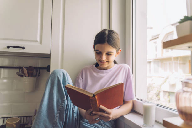istock Beautiful girl reading book on kitchen counter at home. 2136410619