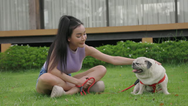 Woman Lovingly Petting Her Pug in the Garden