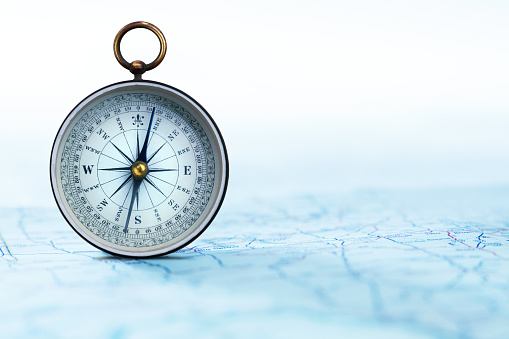 A standing compass on a road map.