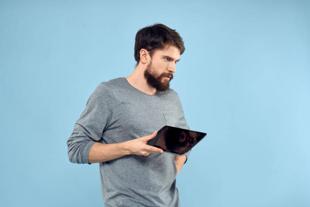 istock Man holding tablet in hands wireless technology internet lifestyle studio blue background emotions 2136437222