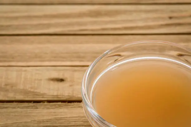 unfiltered, raw apple cider vinegar with mother - a small glass bowl on wooden table