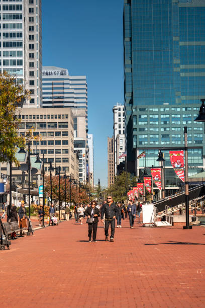 Baltimore, Maryland USA - October 29, 2022:  People walk along the boardwalk paths and downtown marina on the Inner Harbor of Baltimore Maryland flowing out to the Patapsco River and Chesapeake Bay