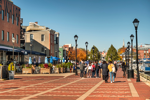 Baltimore, Maryland USA - October 29, 2022:  People walk along the boardwalk paths and the chic restaurants and taverns of Fells Point in Baltimore Maryland flowing on the Patapsco River and Chesapeake Bay
