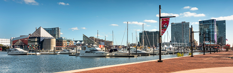Baltimore, Maryland USA - October 29, 2022:  People walk along the boardwalk paths and downtown marina on the Inner Harbor of Baltimore Maryland flowing out to the Patapsco River and Chesapeake Bay