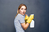 Cleaning lady in yellow rubber gloves detergents home care gray background
