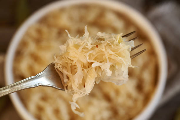 Homemade fermented cabbage or sauerkraut on a metal fork, closeup