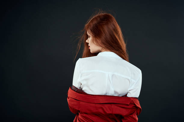 Woman in red jacket white shirt back view dark background. High quality photo