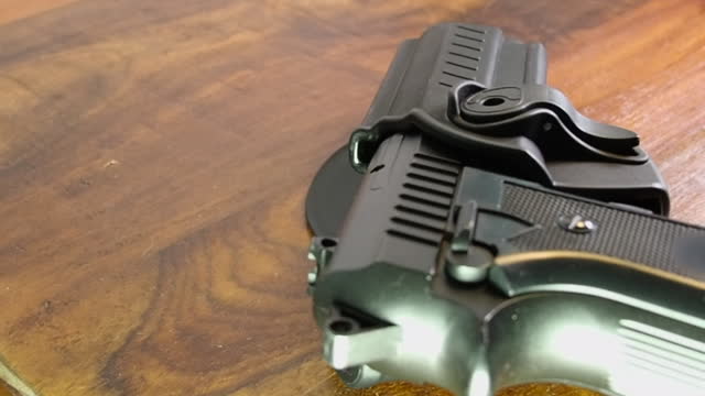 Close-up weapon: Handgun pistol in holster sitting on wooden table