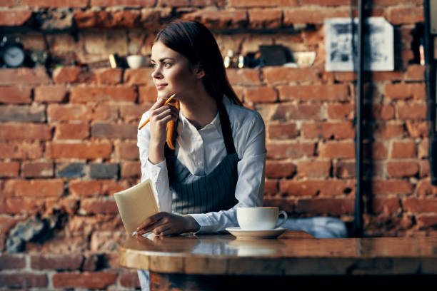 istock woman waiter coffee cup Near the table brick wall 2136540491