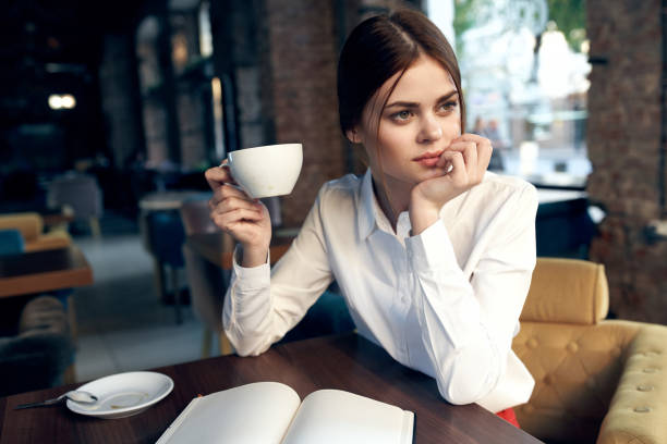 istock woman in a restaurant with a notepad on the table and a cup in hand 2136541546