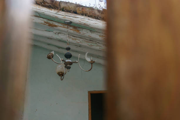 An old ceiling light in an abandoned building seen through wooden door