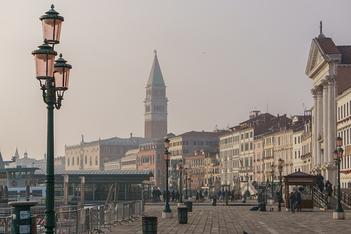 View from the waterfront Riva degli Schiavoni at the distant Tower of San Marco with Doge Palace on a hazy winter day, Venice, Veneto, Italy