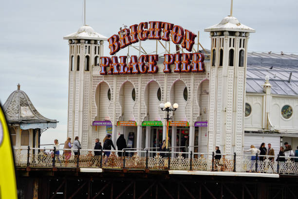 Brighton, Brighton And Hove, East Sussex, Southeastern England, United Kingdom, Britain, Europe - 16th March 2024: Brighton Seafront. The Brighton palace pier structure and facade near the Brighton beach. Some people are also seen from the distance walking on the structure.Location: Brighton Palace Pier is located at Madeira Drive, Brighton, BN2 1TW, in the city centre opposite the Old Steine.Its Structure and Attractions as seen in the photo:Brighton Palace Pier, a Grade II listed pleasure pier building, features a variety of attractions including traditional British architecture, modern entertainment facilities, fairground rides, roller coasters, restaurants, arcades, and some Restaurants. a waterfront theme park in England.The seafront of Brighton and Hove in England;  a picturesque view of the beach, a sought-after travel destination in the UK. A vibrant atmosphere and charming coastal town appeal, Brighton and Hove's  panoramic view that captivates tourists from all over.
