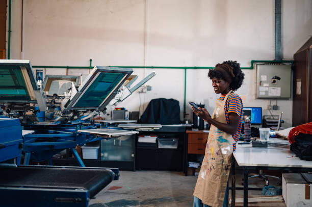 istock Interracial silkscreen printing shop worker taking orders on cellphone 2136635336