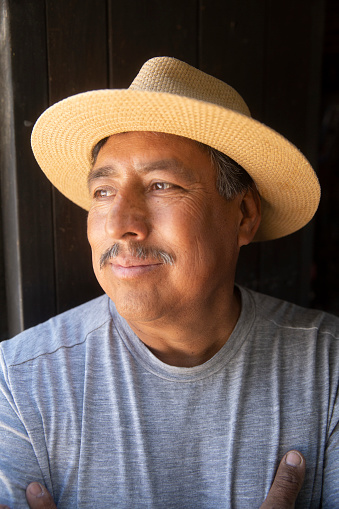A nice looking middle aged man wearing a straw hat, looking away.