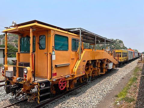 The ballast tamping machine is parking after works to maintain the sleeper and ballast stone in the new railway line of the double track project, front view with the copy space.