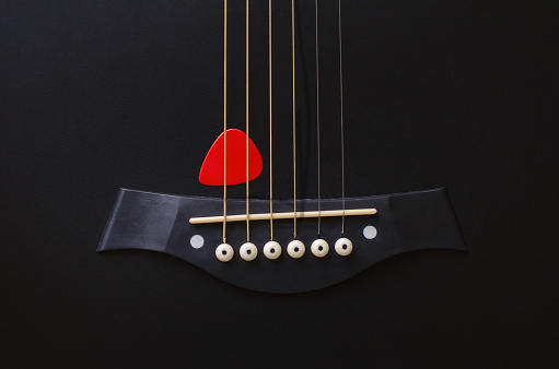 Mediator and black six-string guitar. Musical background for your business