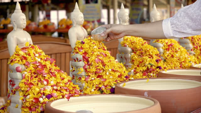 Woman hand pouring down  water to Buddha statue during the Songkran festival in Thailand.
