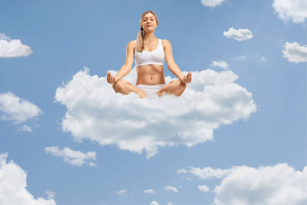 istock Young woman meditating on clouds up in the sky 2136755493