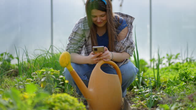 SLO MO Panning Shot of Happy Young Woman Using Smartphone in Greenhouse
