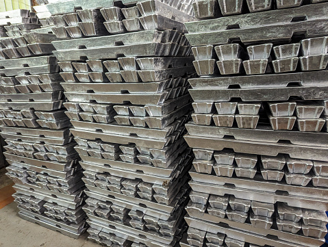 Several stacks of aluminum bars arranged, in a warehouse.