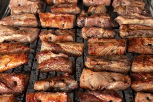 Barbecue at the cottage. May holidays. Barbecue in nature. The process of cooking meat on the grill, close-up. Barbecue of pork ribs on the grill.