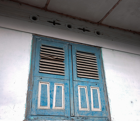 A blue wooden house window, ancient style, with white walls.