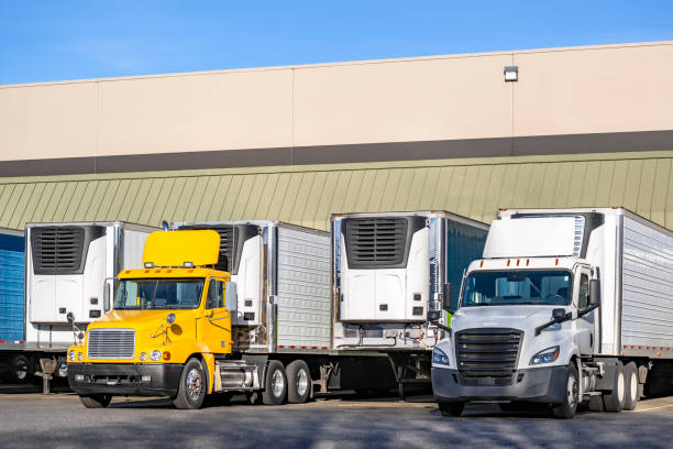 istock Different big rigs semi trucks with refrigerator semi trailer standing on the warehouse dock gates loading cargo for the next delivery route 2136896298