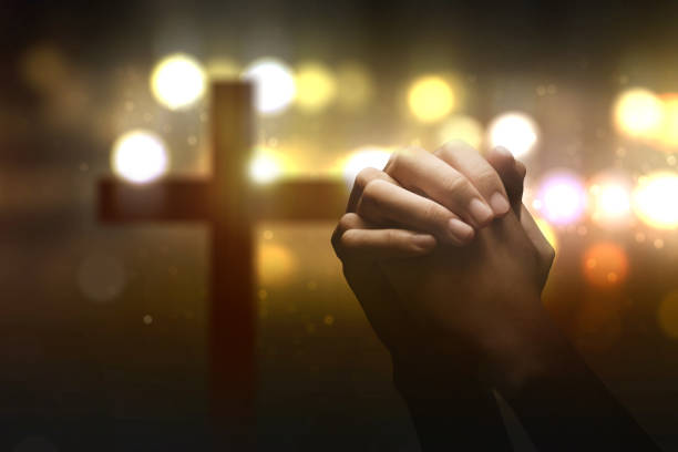 Christian man praying with raised hands on a blurred light background. Christian concept